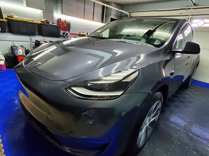 A tesla model y is parked in a garage.