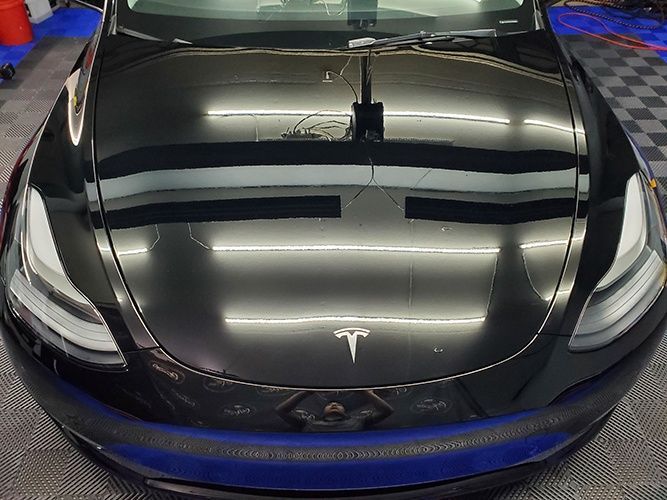 A black tesla model 3 is parked in a garage.