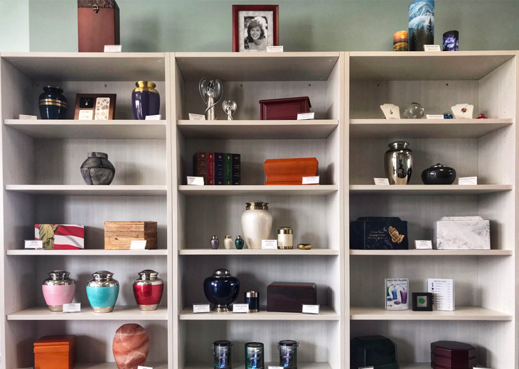 Shelves displaying a variety of urns for ashes, with a framed photo at the top.