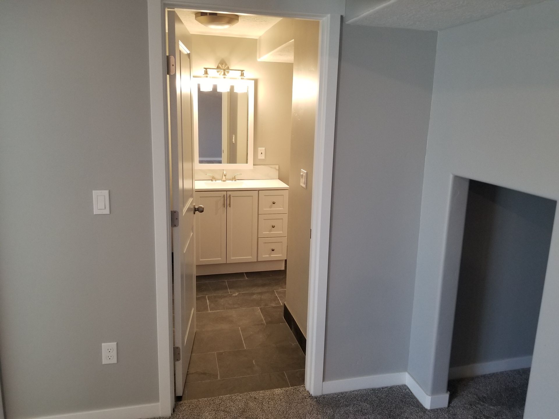 A bathroom with a sink , mirror and stairs leading to it.