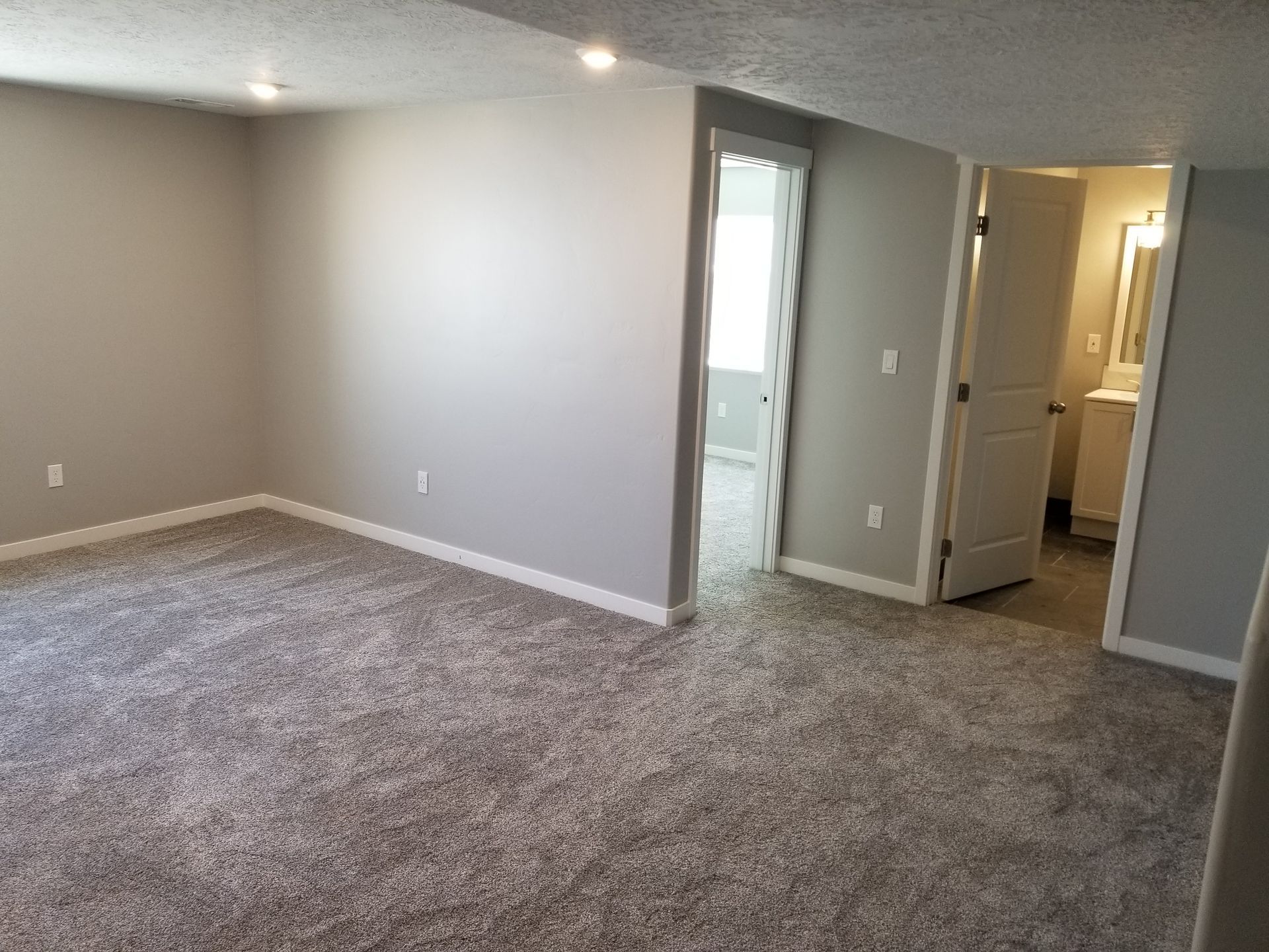 An empty room with a carpeted floor and gray walls.