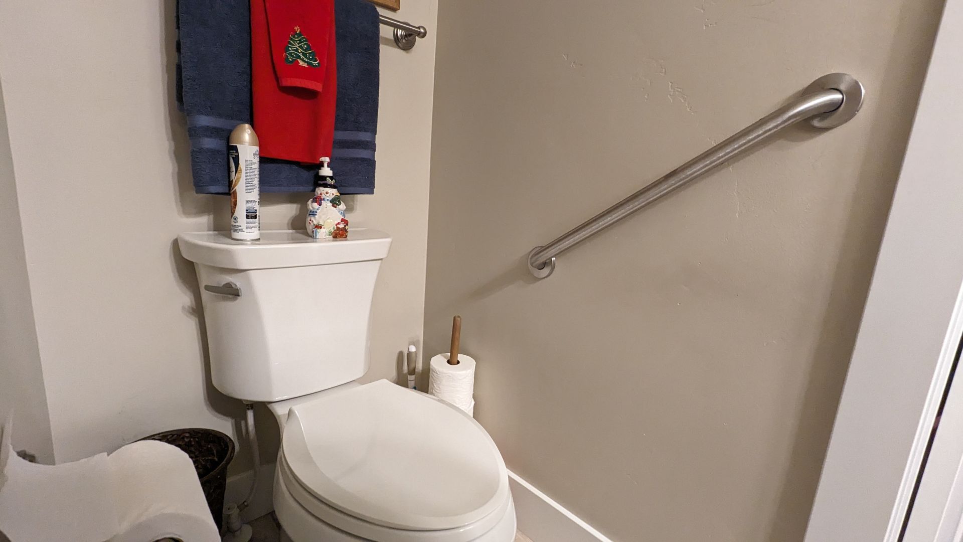 A bathroom with a toilet and a hand rail.