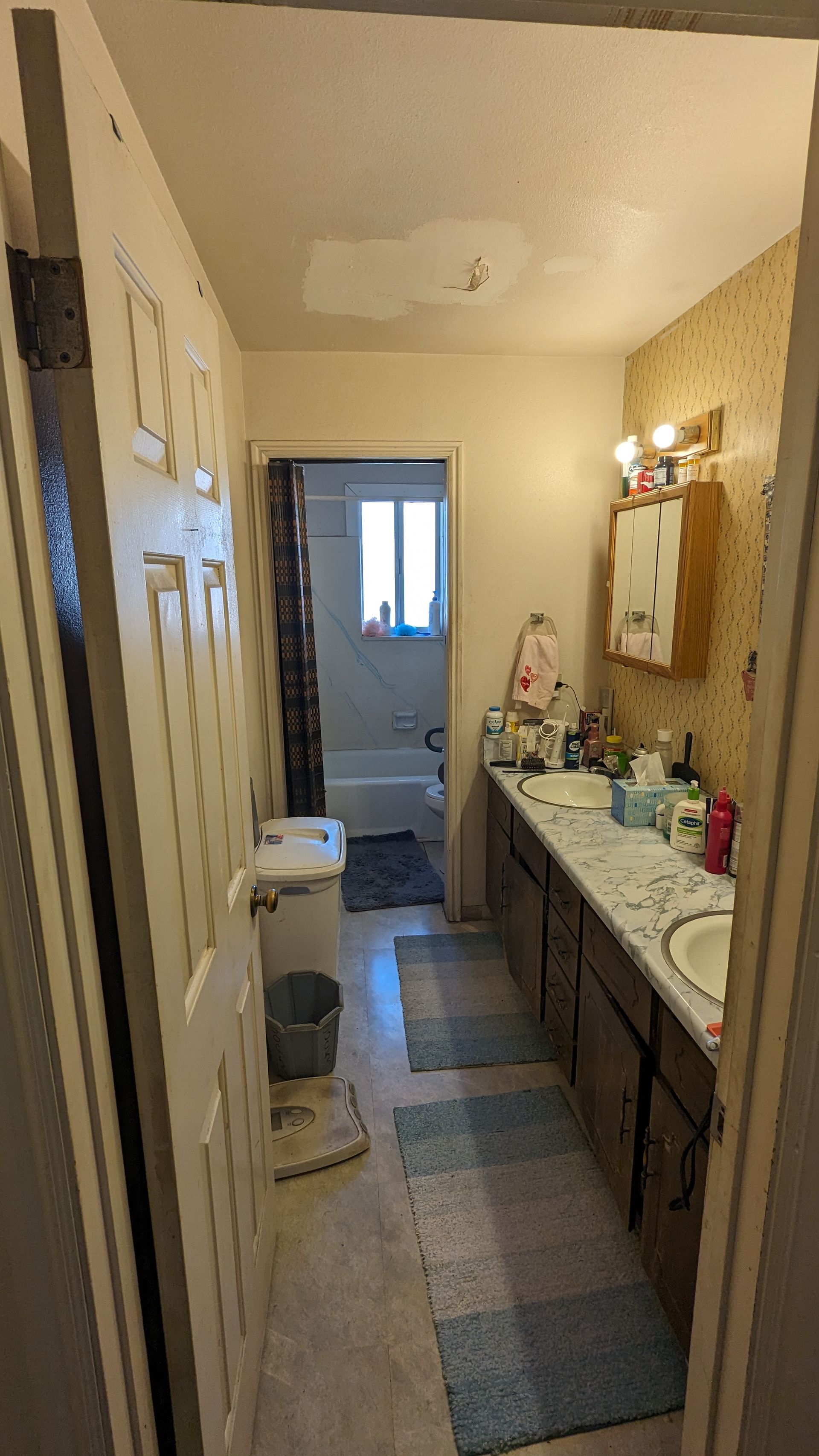 A bathroom with two sinks , a toilet , and a window.