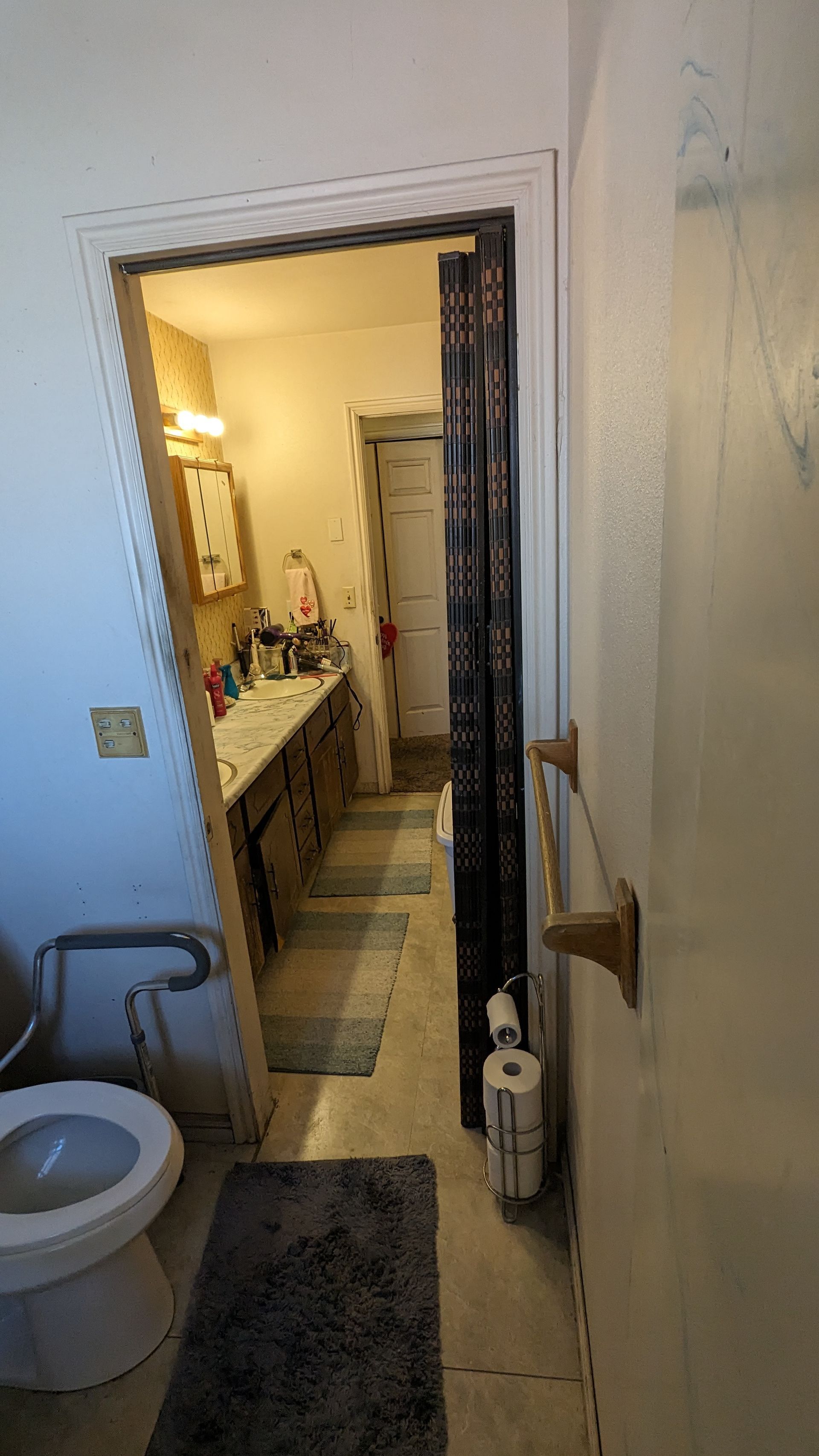 A bathroom with a toilet , sink , and towel rack.