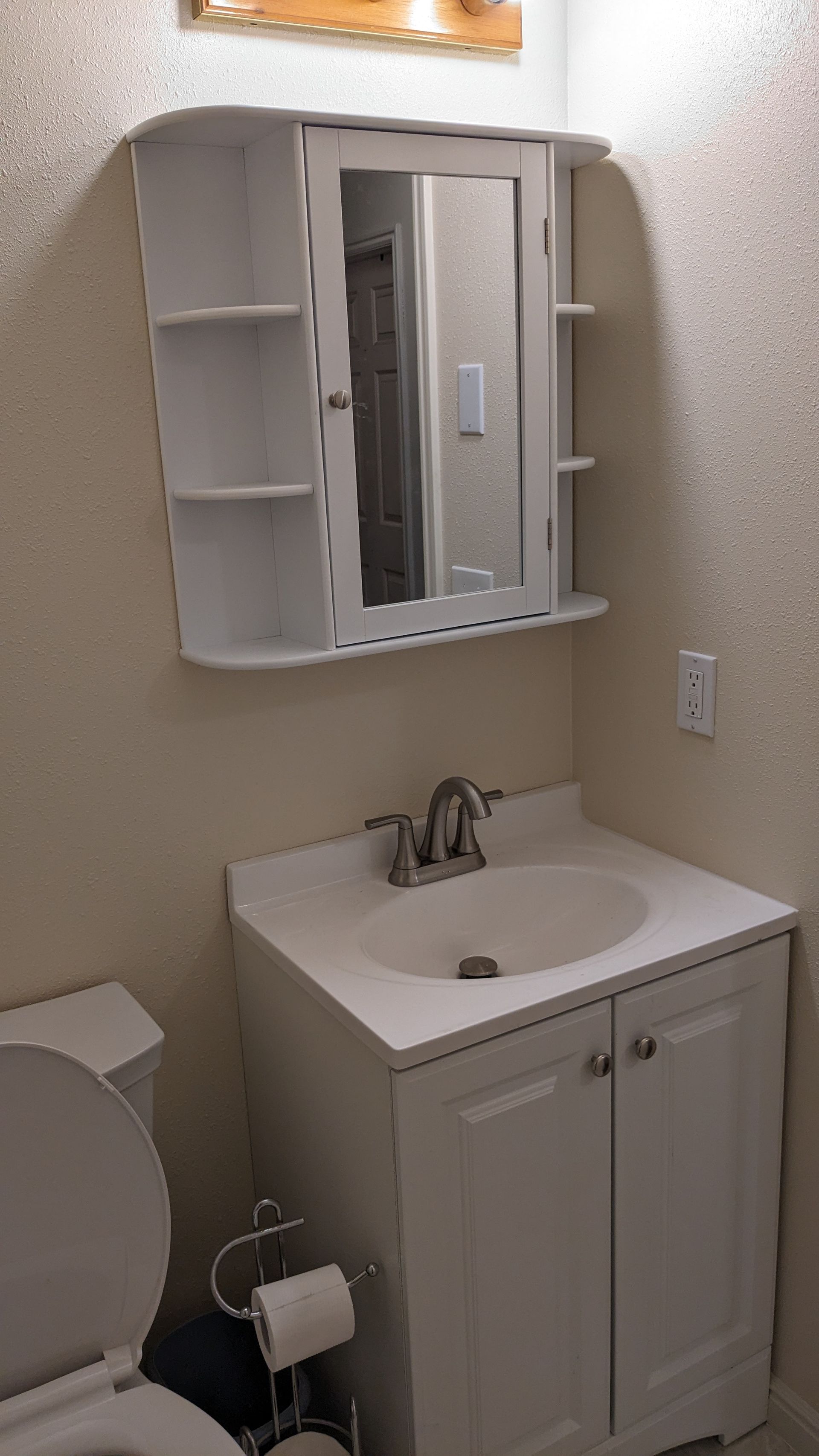 A bathroom with a sink , toilet and mirror.