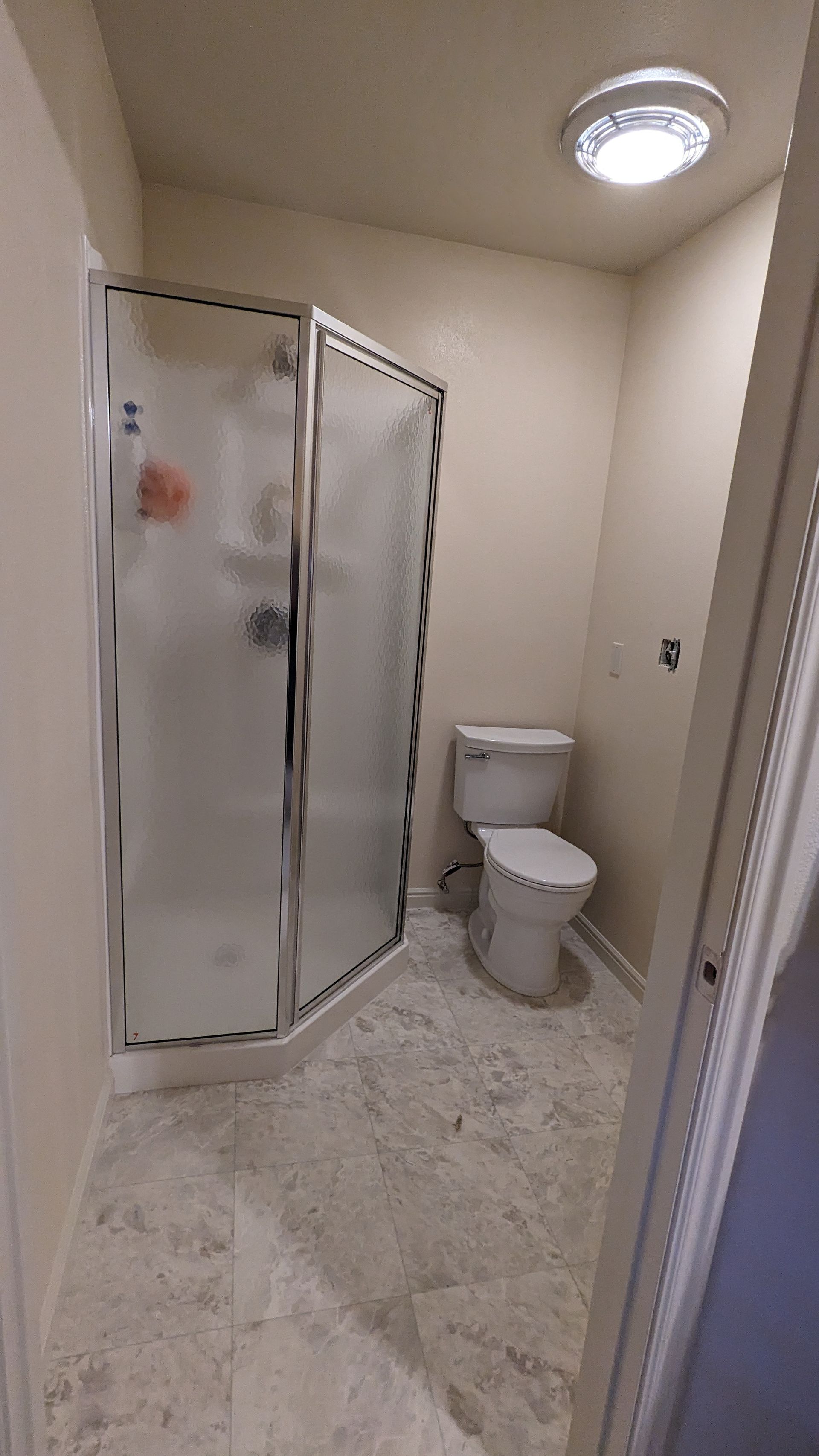 A bathroom with a toilet and a shower stall.
