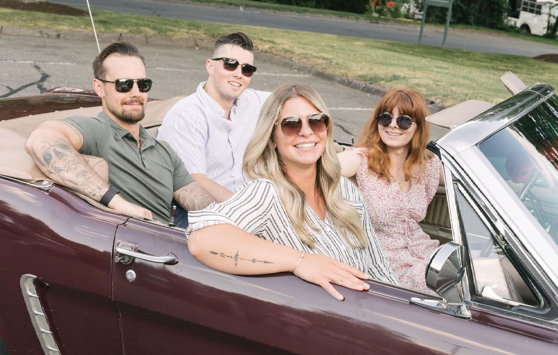 An image of a group of people are sitting in a convertible car