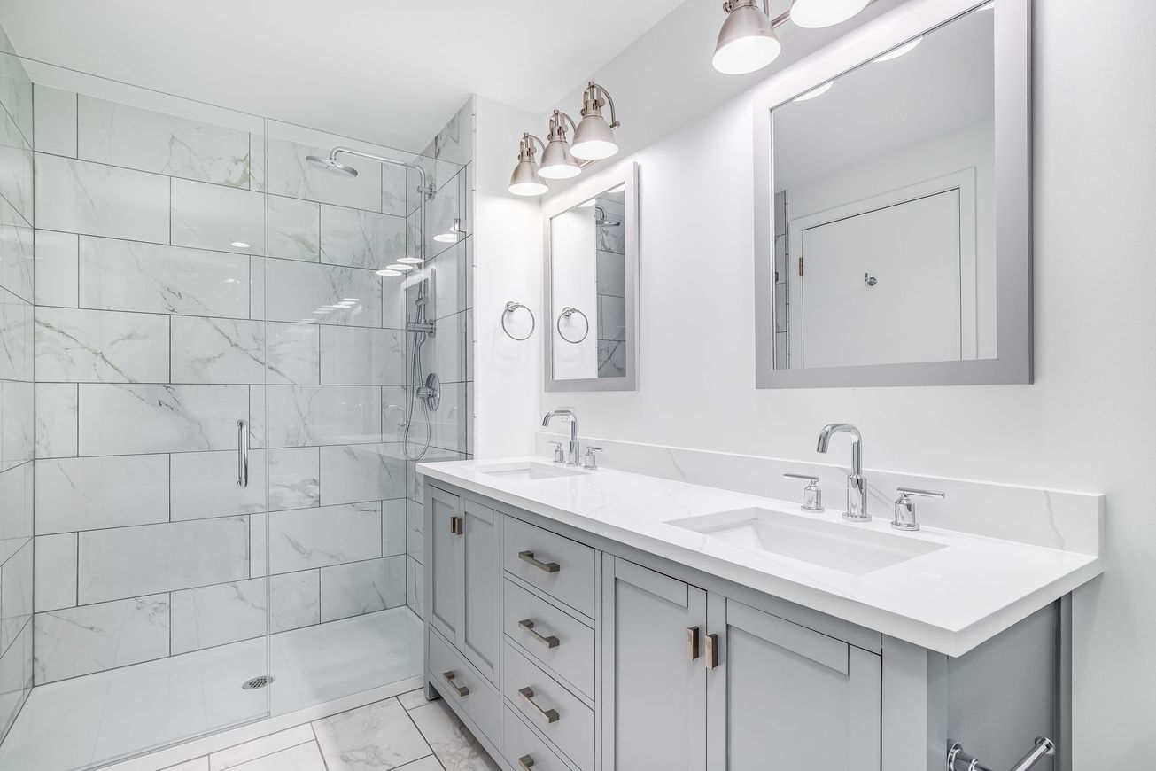 A bathroom with two sinks and a walk in shower.