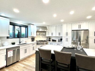 A kitchen with white cabinets and stainless steel appliances and a large island.