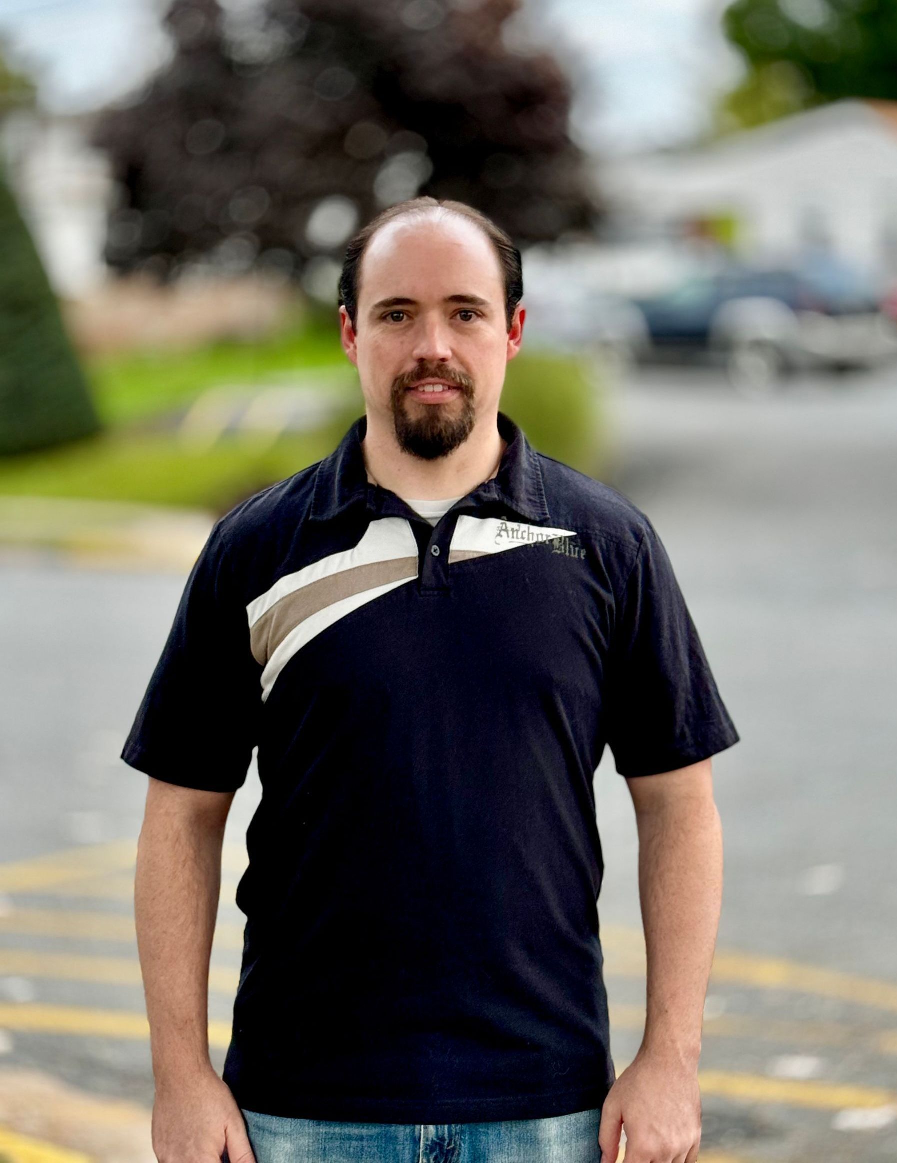 A man with a beard wearing a black polo shirt