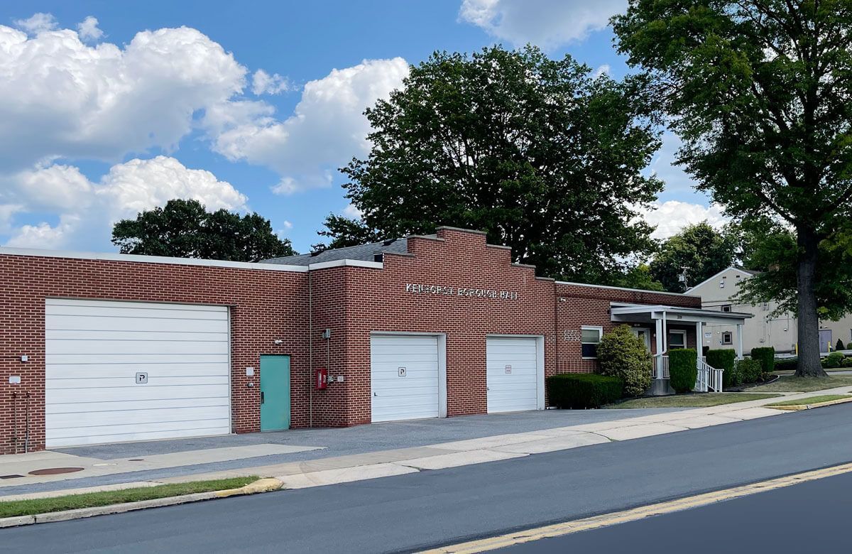 A brick building with white garage doors and a green door