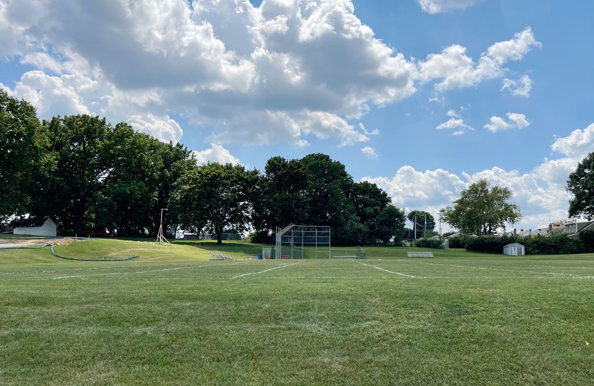 A soccer field with a goal and trees in the background on a sunny day.