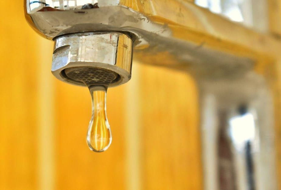 A close up of a faucet with a drop of water coming out of it.