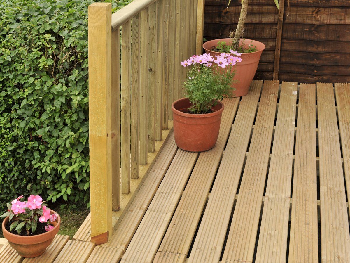 House with wooden decking and patio leading to garden