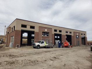 A white truck is parked in front of a building under construction.