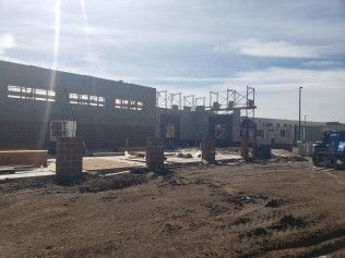 A large building is being built in the middle of a dirt field.