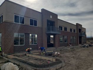 A group of construction workers are working on a large brick building.
