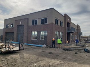 A group of construction workers are standing in front of a large building under construction.