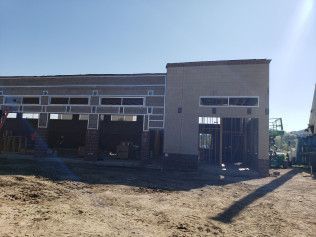 A large building is being built in a dirt field.