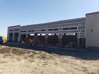 A large building is being built in the middle of a dirt field.