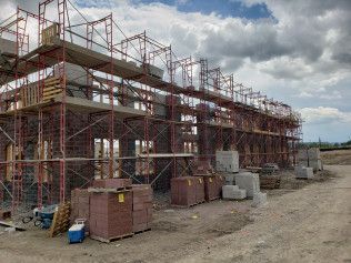 A large building is being built with scaffolding and bricks.