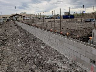 A brick wall is being built in a dirt field.