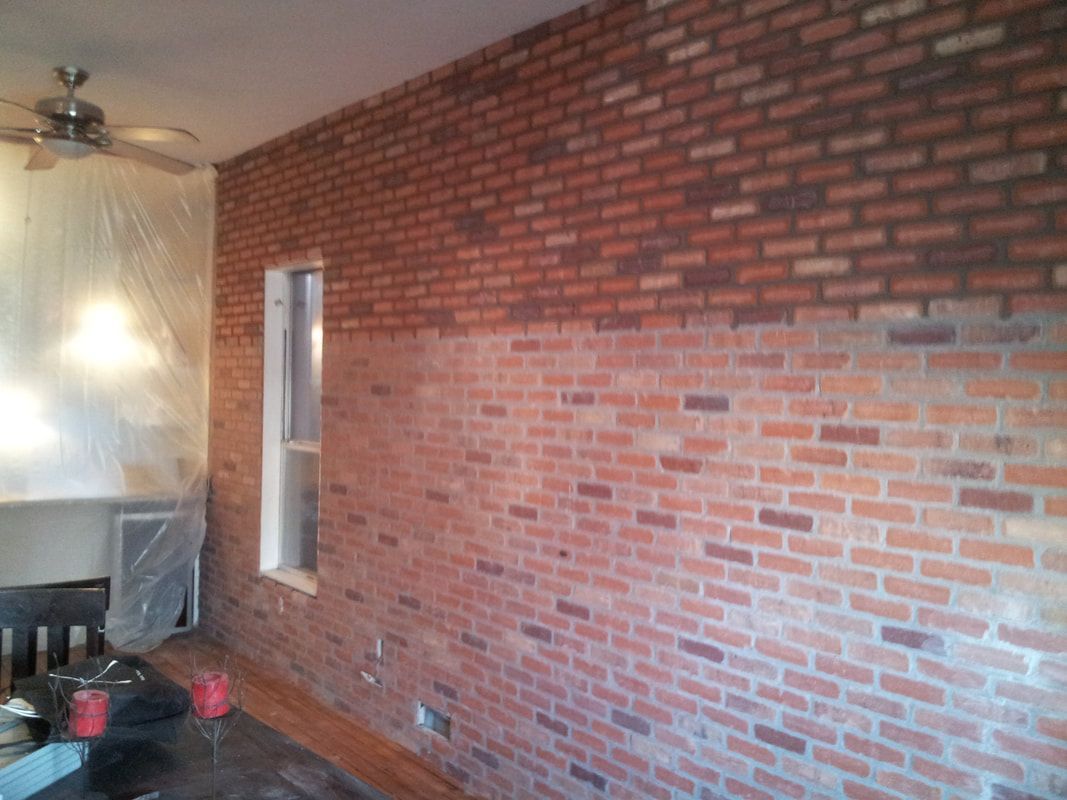 A living room with a brick wall and a window.