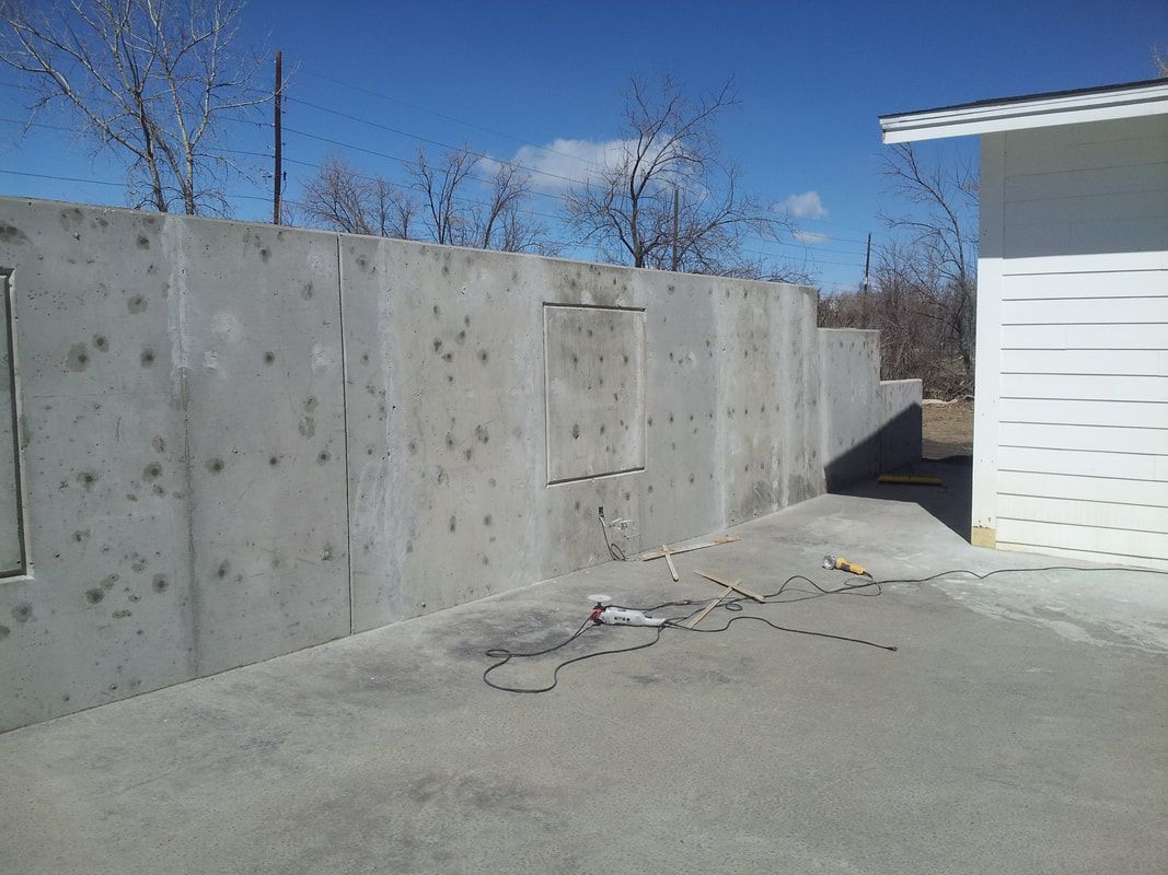 A concrete wall is being built next to a white building.
