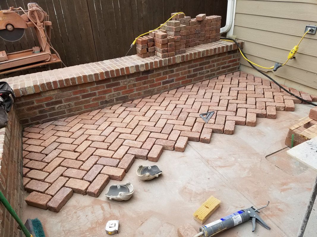 A brick walkway is being built in a herringbone pattern.