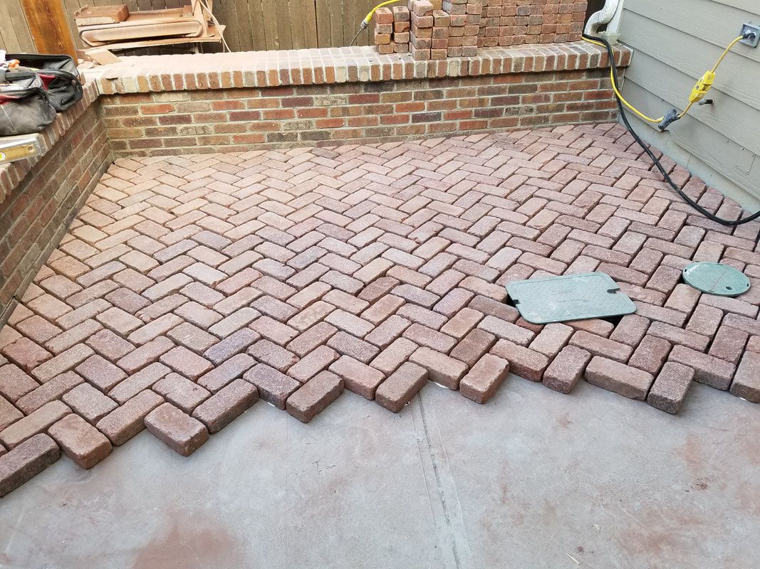 A brick patio is being built in a herringbone pattern.