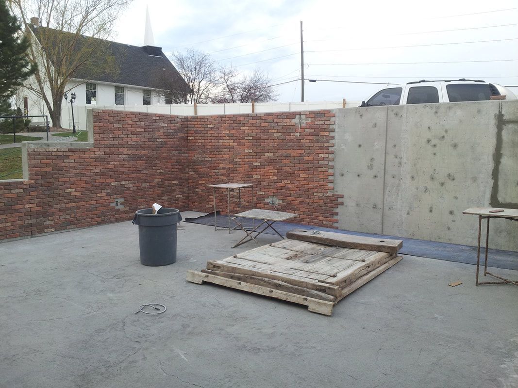 A brick wall with a trash can in front of it