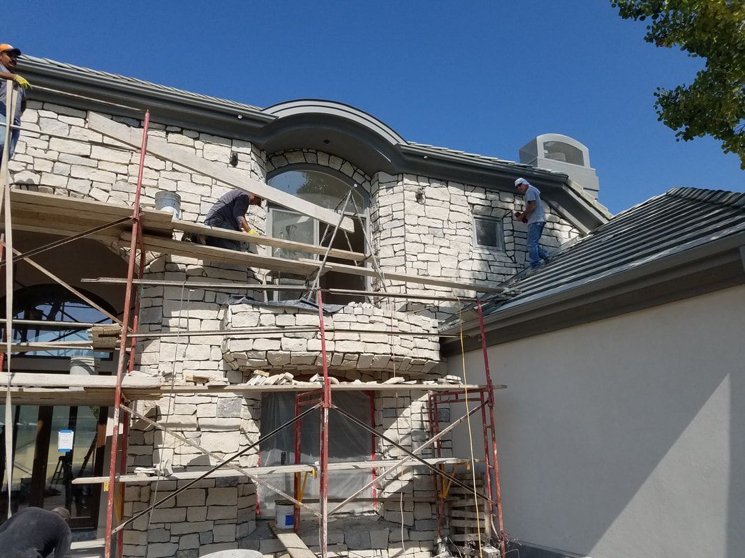 A man is standing on a scaffolding on the roof of a house.
