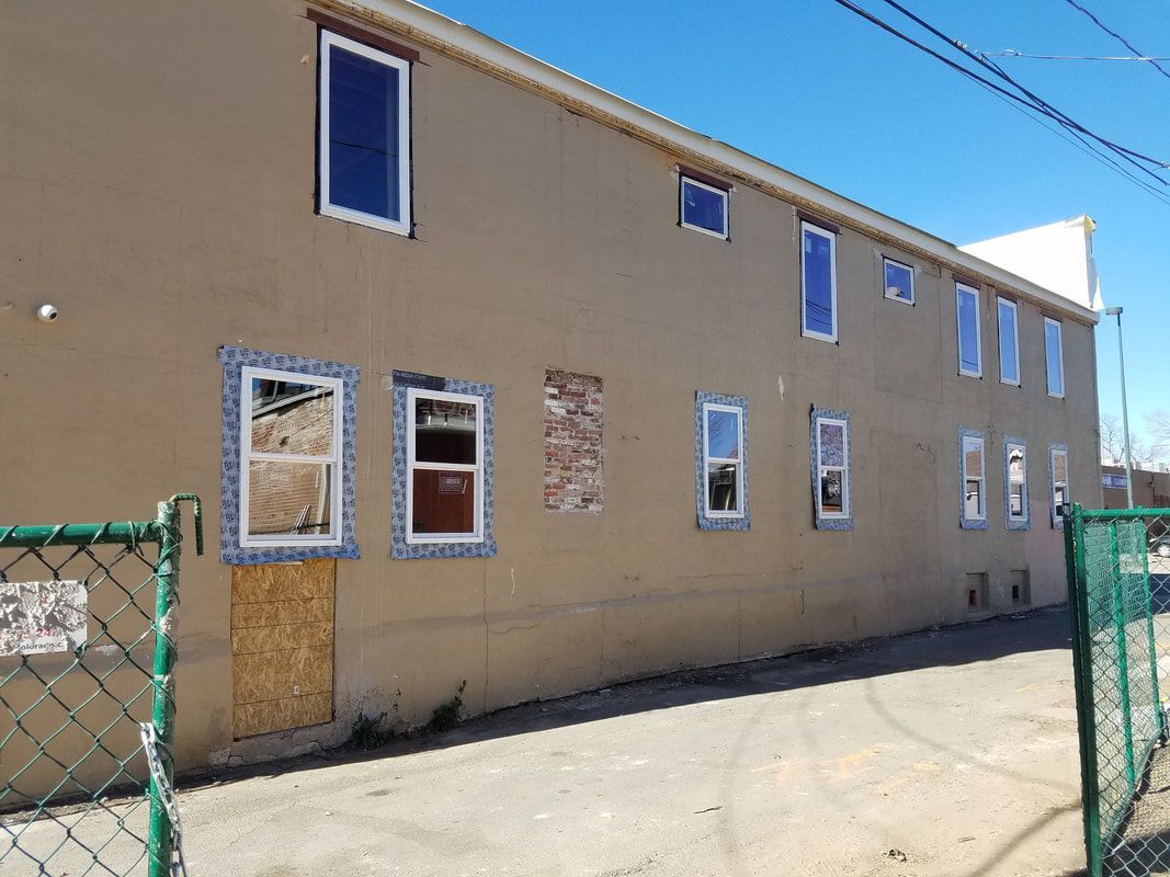 A building with a lot of windows is behind a chain link fence.