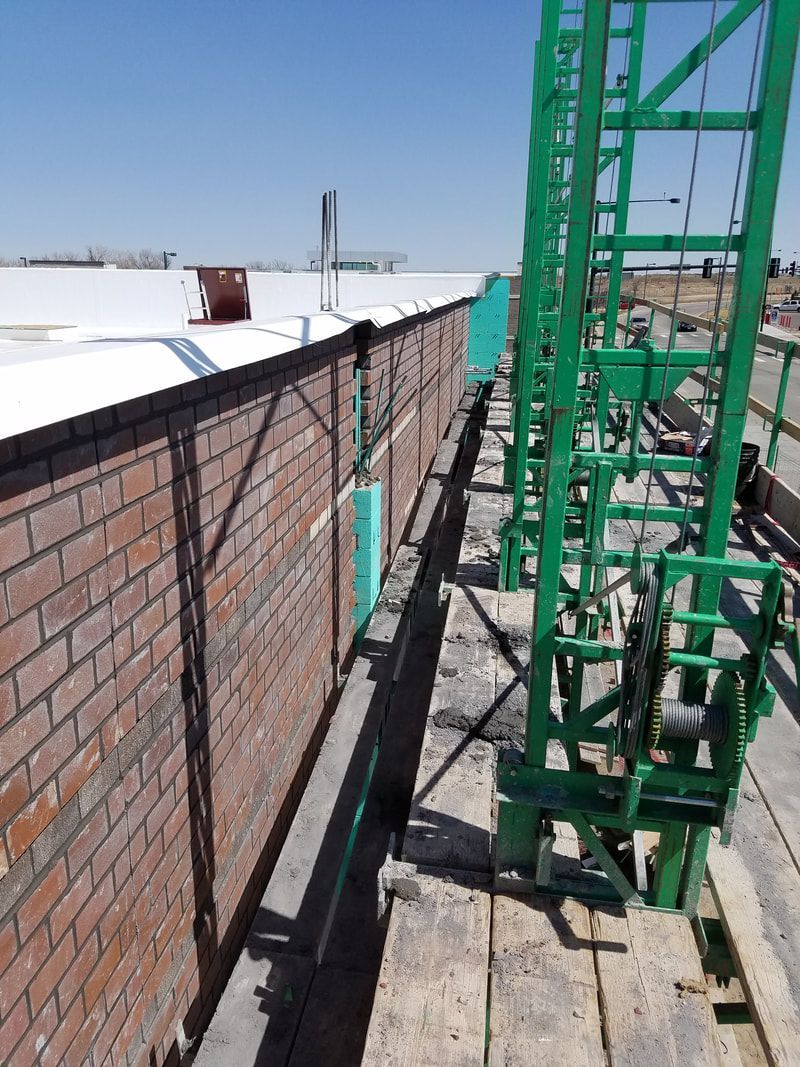 A green ladder is next to a brick wall