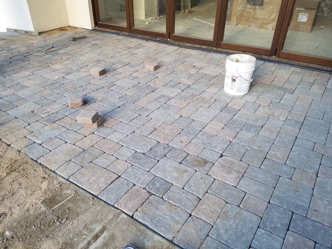 A white bucket is sitting on top of a brick patio.