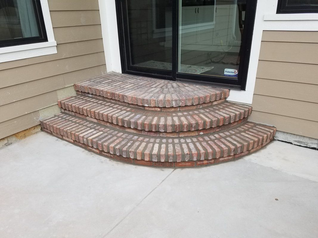 A set of brick steps leading up to a sliding glass door.