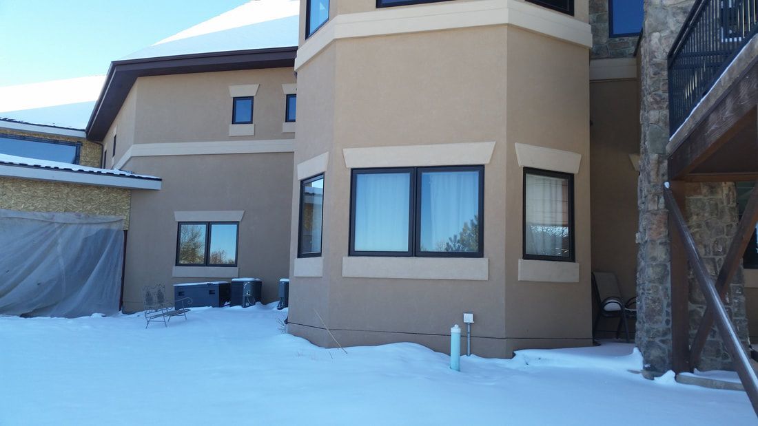 A large house with a lot of windows is covered in snow.