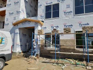 A white van is parked in front of a building under construction.