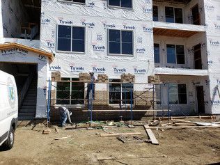 A building under construction with scaffolding and a white van parked in front of it.