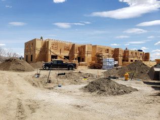 A truck is parked in front of a large building under construction.