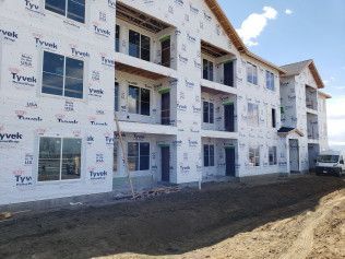 A large apartment building is being built in the middle of a dirt field.