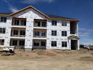 A large apartment building is being built in the middle of a dirt field.