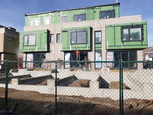 A building under construction with a chain link fence in front of it.