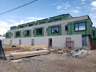 A building under construction with a lot of windows and a lot of wood in front of it.