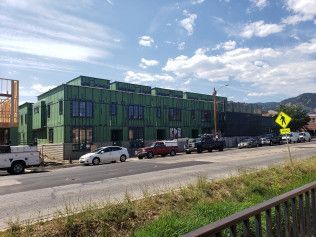 A building under construction with cars parked in front of it.