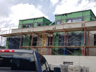 A truck is parked in front of a building under construction.