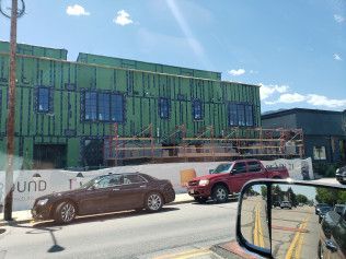 A car is parked in front of a building under construction.