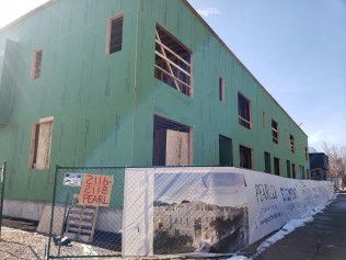 A large green building under construction with a fence around it.
