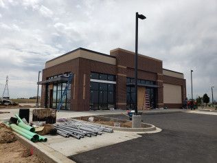 A large brick building is being built next to a parking lot.