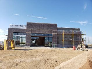 A large brick building is being built in a dirt field.